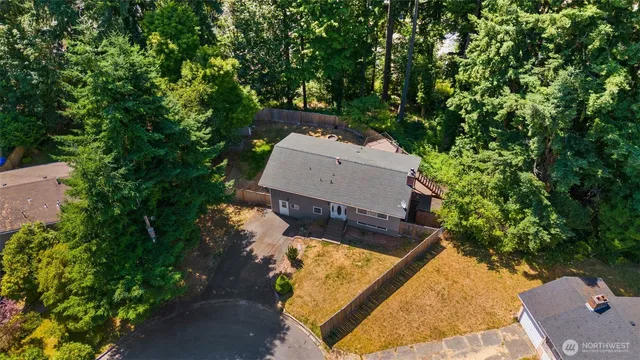 an aerial view of a house with a yard and trees all around