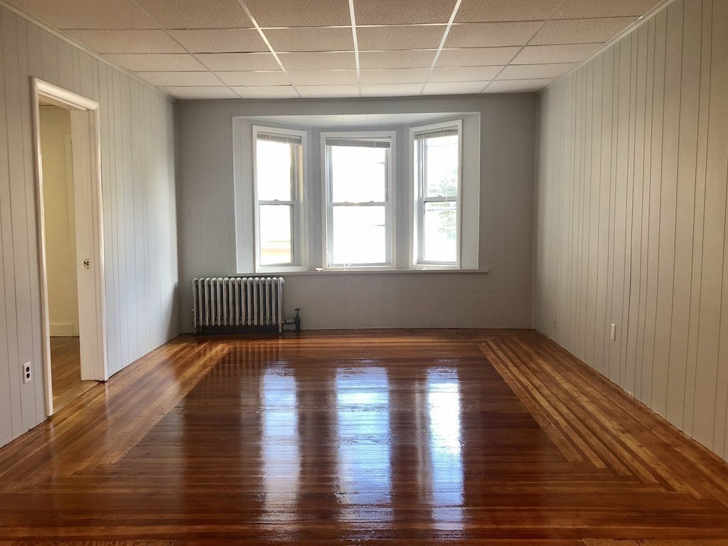 74 Pearson Avenue, Unit 2 Somerville, MA 02144 - Photo 4 of 11 a view of an empty room with wooden floor and a window