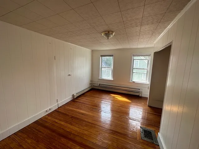 a view of empty room with wooden floor and fan