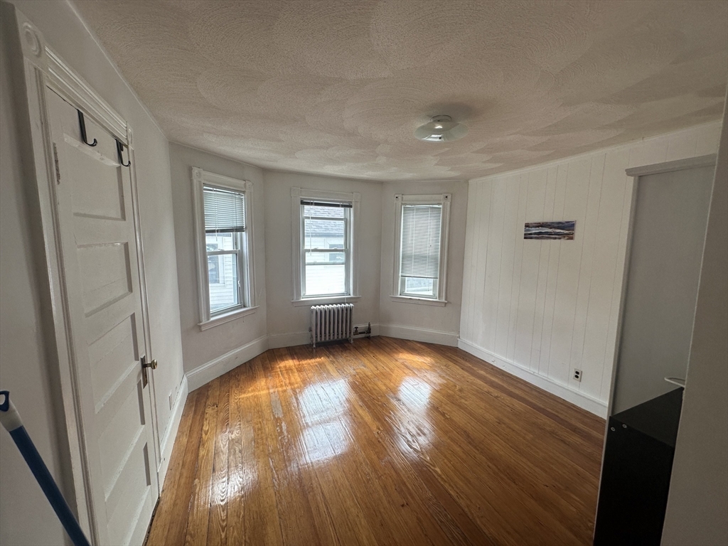 74 Pearson Avenue, Unit 2 Somerville, MA 02144 - Photo 7 of 11 an empty room with wooden floor and windows