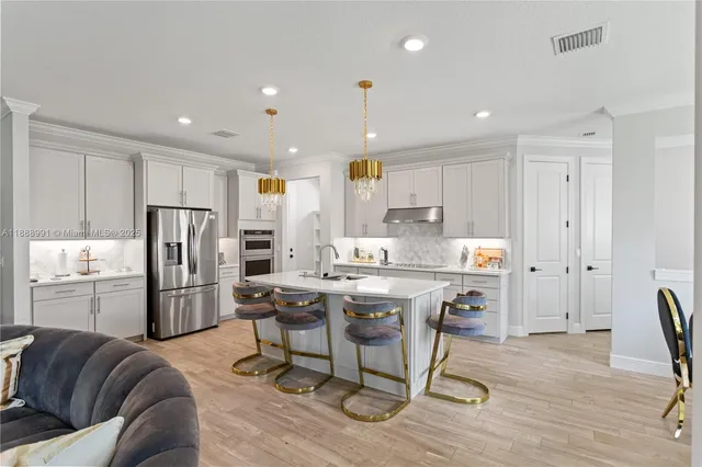 a kitchen with stainless steel appliances kitchen island granite countertop a refrigerator and a stove top oven