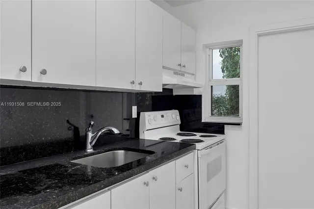 a kitchen with granite countertop white cabinets and sink