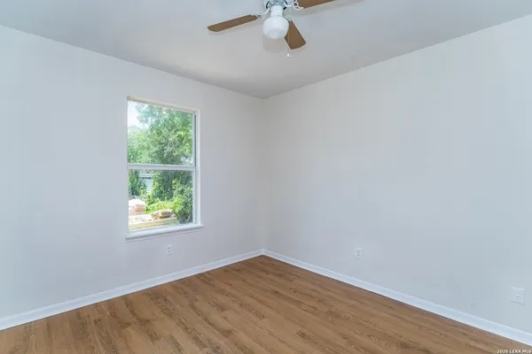 an empty room with a window and a ceiling fan