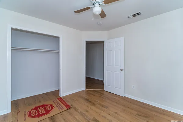 a view of an empty room with a ceiling fan window and closet area