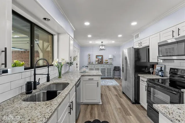 a kitchen with kitchen island granite countertop a sink counter top space stainless steel appliances and cabinets