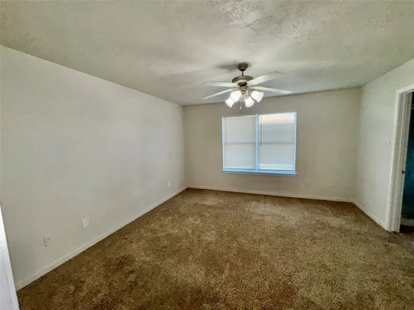 an empty room with windows and chandelier fan