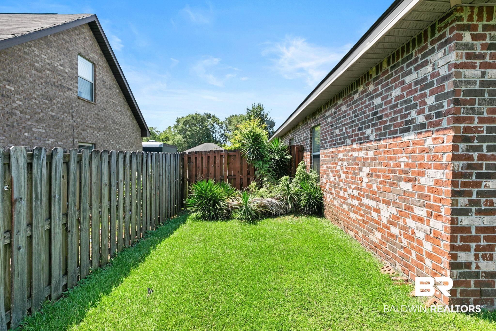 2216 Livingstone Court Mobile, AL 36695 - Photo 44 of 62 Side yard featuring a red brick exterior, green lawn, and wood privacy fencing