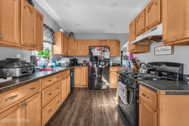 a kitchen with stainless steel appliances granite countertop a stove top oven a sink dishwasher and cabinets with wooden floor