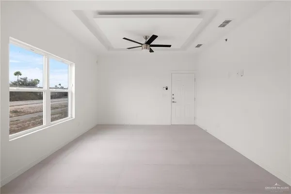 an empty room with windows and ceiling fan