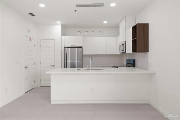 a large white kitchen with kitchen island a sink a stove and refrigerator