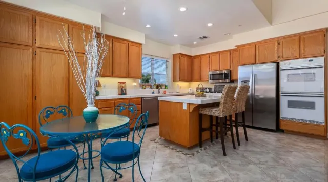 a kitchen with stainless steel appliances granite countertop a dining table chairs sink refrigerator and cabinets