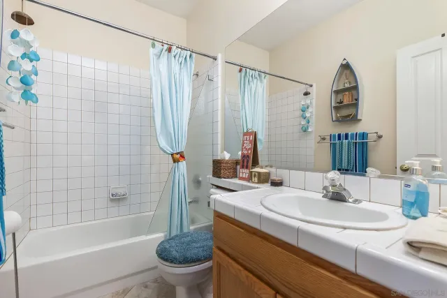 a bathroom with a granite countertop sink a toilet and shower