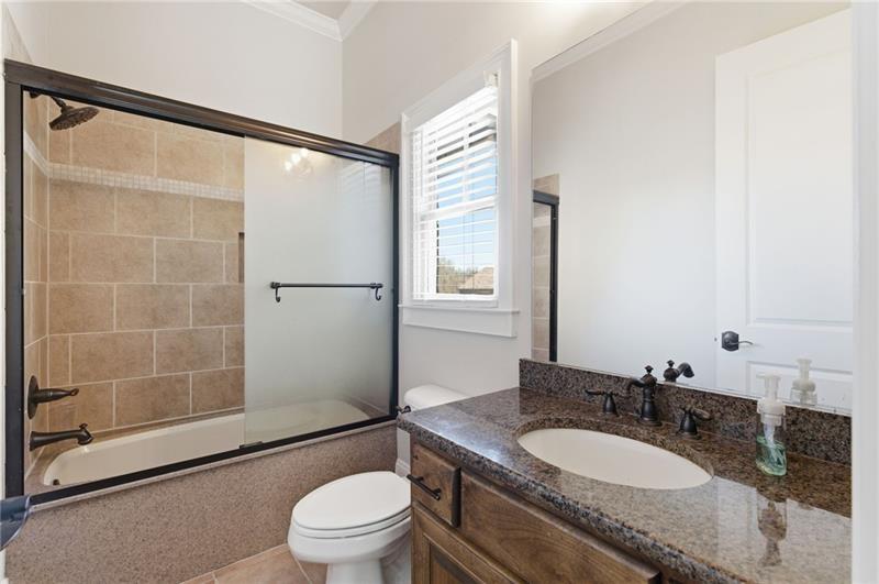1565 Bramble Bush Way Suwanee, GA 30024 - Photo 17 of 62 a bathroom with a granite countertop sink toilet a mirror and shower