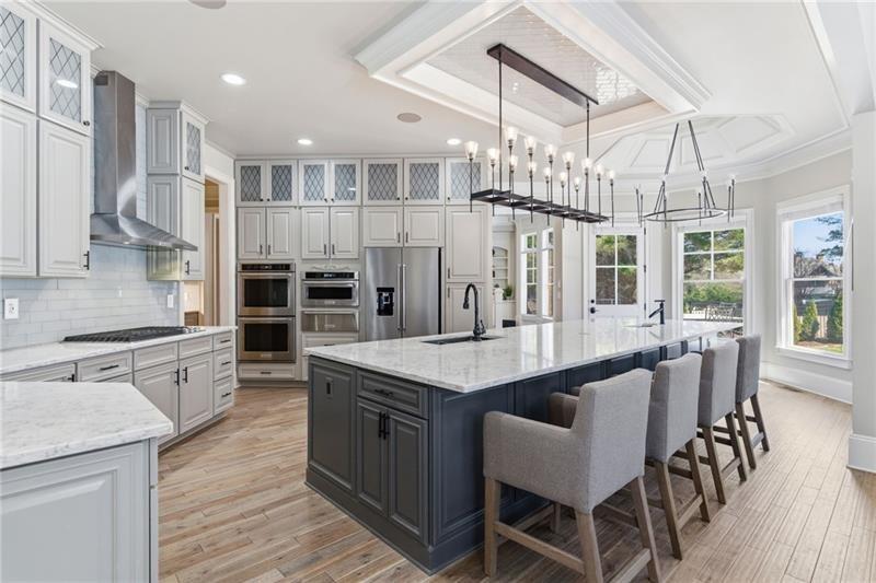 1565 Bramble Bush Way Suwanee, GA 30024 - Photo 19 of 62 a large kitchen with stainless steel appliances kitchen island granite countertop a table chairs in it and wooden floors