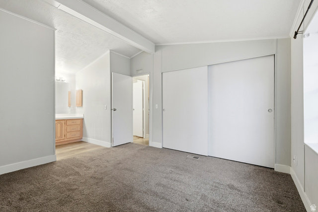 150 West 7500th South, Unit 55 Midvale, UT 84047 - Photo 21 of 28 Unfurnished bedroom with carpet floors, beam ceiling, a closet, and ensuite bath