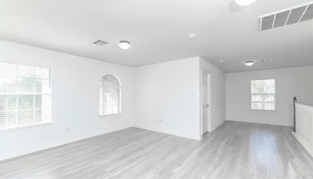 an empty room with wooden floor and windows