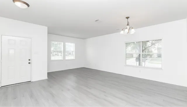 a view of an empty room with a window and wooden floor