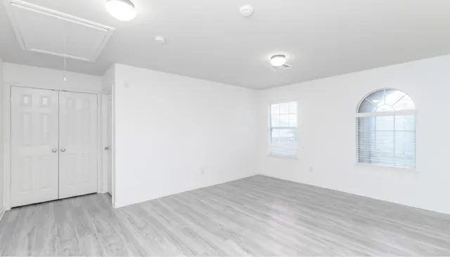 an empty room with wooden floor and windows
