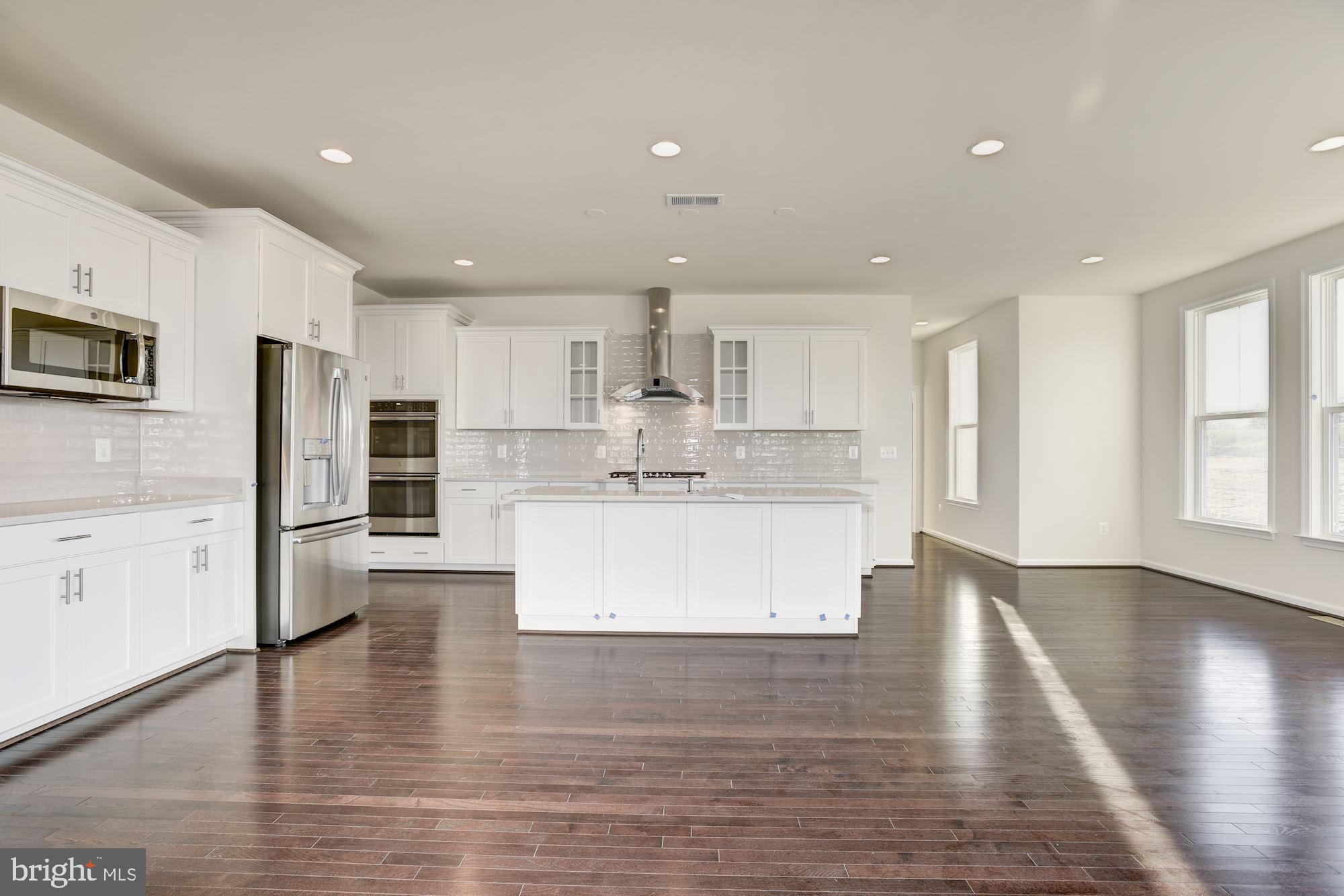 a large kitchen with stainless steel appliances kitchen island wooden cabinets and a refrigerator