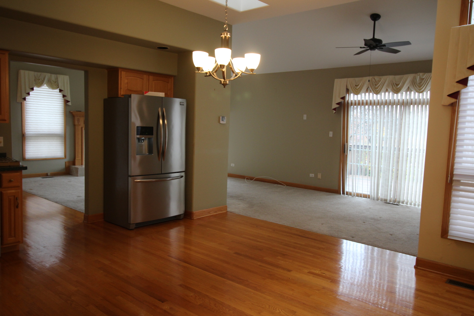 10 Moorings Drive Palos Heights, IL 60463 - Photo 14 of 19 a view of a refrigerator in kitchen and an empty room with wooden floor