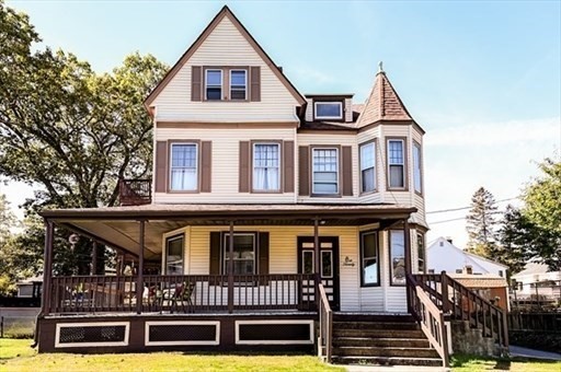 a view of a white house with large windows and a small yard