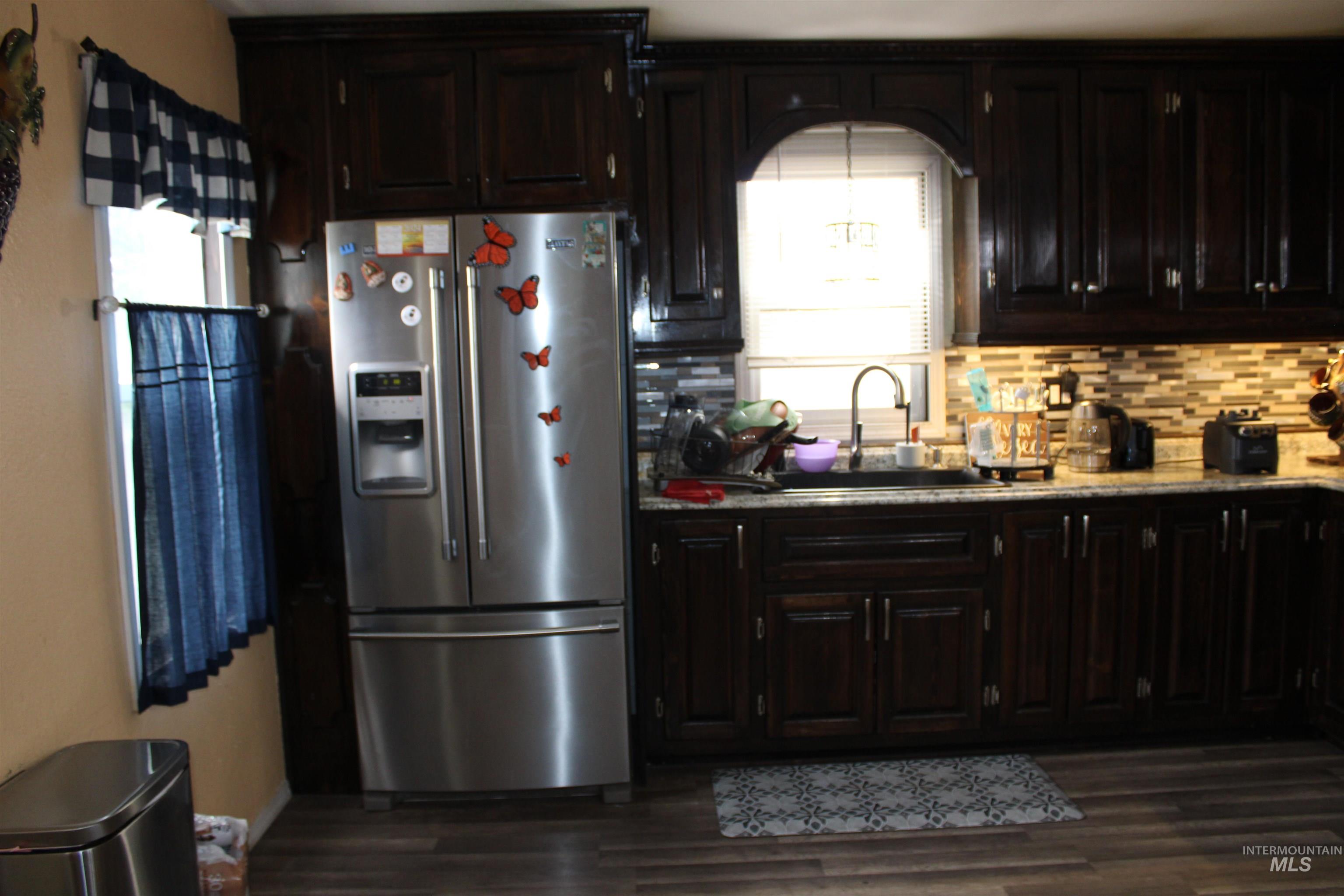 106 3rd Street West Declo, ID 83323 - Photo 6 of 23 Kitchen featuring stainless steel fridge with ice dispenser, healthy amount of natural light, dark wood finished floors, and backsplash