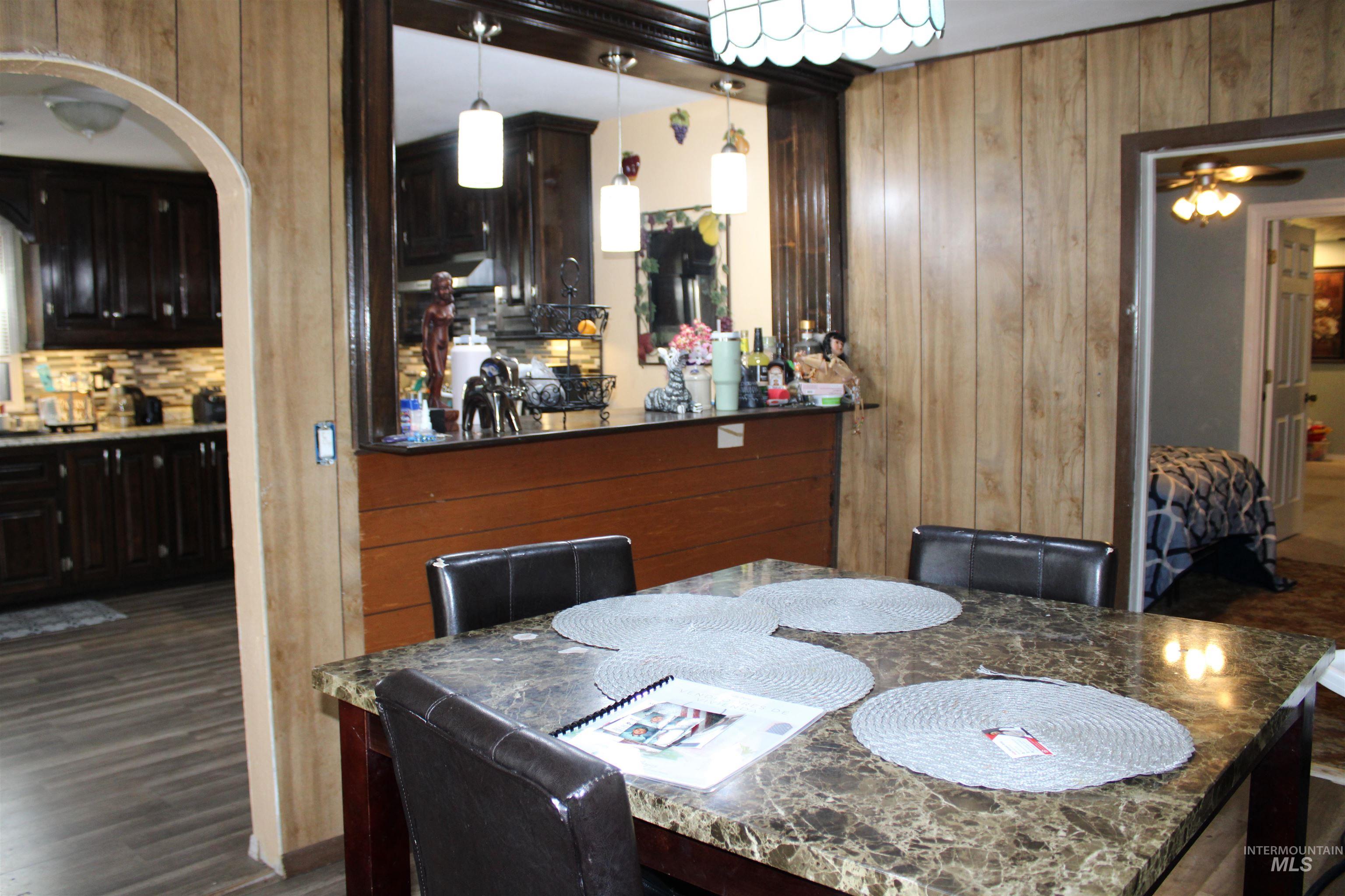 106 3rd Street West Declo, ID 83323 - Photo 7 of 23 Dining room with wood walls, dark wood-type flooring, and arched walkways