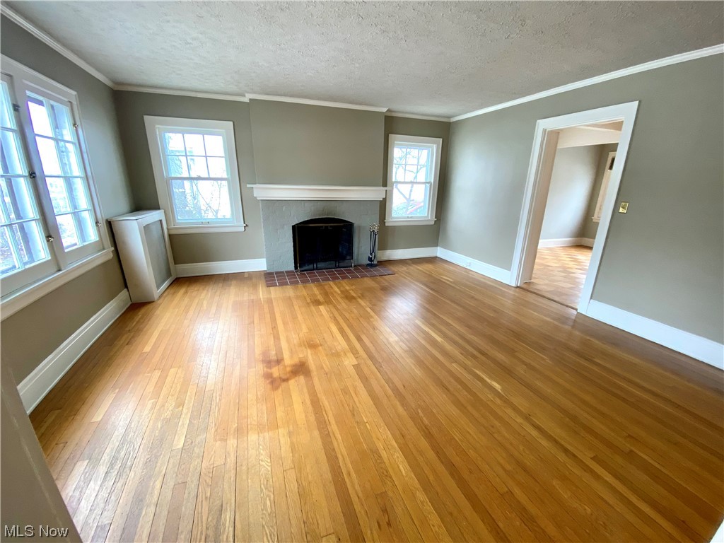 2927 Huntington Road Cleveland, OH 44120 - Photo 2 of 12 Hardwood floored living room featuring ornamental molding, a fireplace, and a textured ceiling