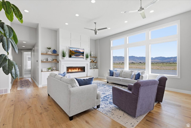 21 Pier Place Tooele, UT 84074 - Photo 10 of 112 Spacious living area featuring large picture windows, a modern linear fireplace, and wood-finish flooring