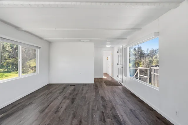 a view of an empty room with a window and wooden floor