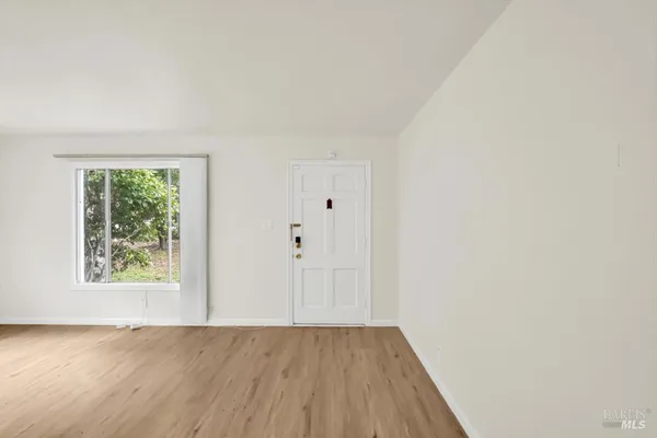 an empty room with wooden floor and window