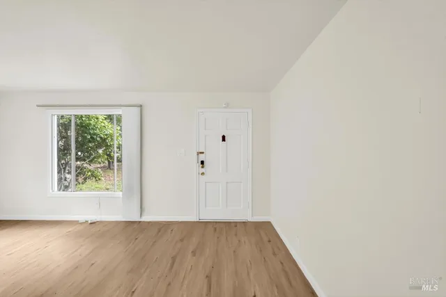 an empty room with wooden floor and window