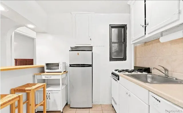 a kitchen with stainless steel appliances a refrigerator a sink and white cabinets