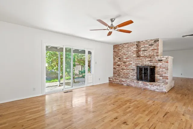 a view of an empty room with wooden floor and a fireplace