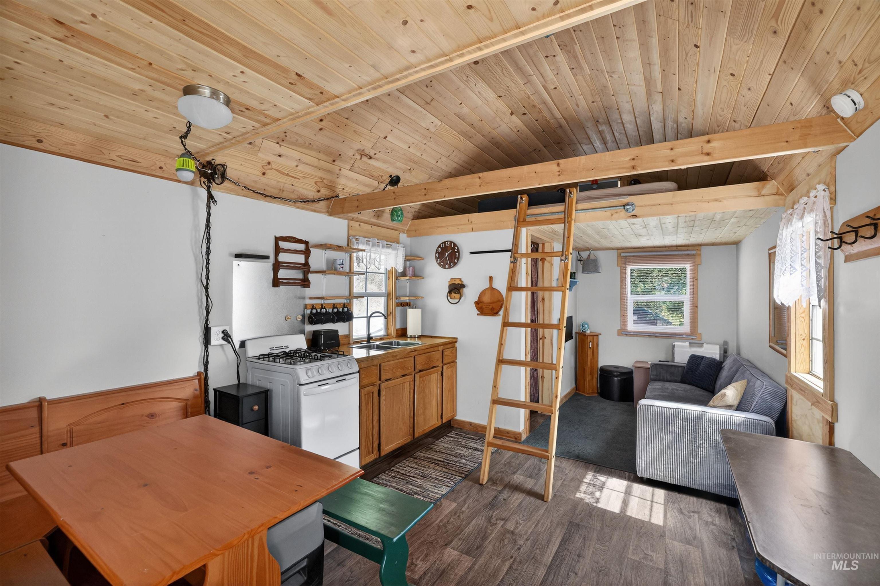 506 Hilltop Road Cascade, ID 83611 - Photo 36 of 36 Kitchen featuring a wooden ceiling with exposed beams, wood finish cabinetry, dark wood-style floors, white gas stove, and open floor plan