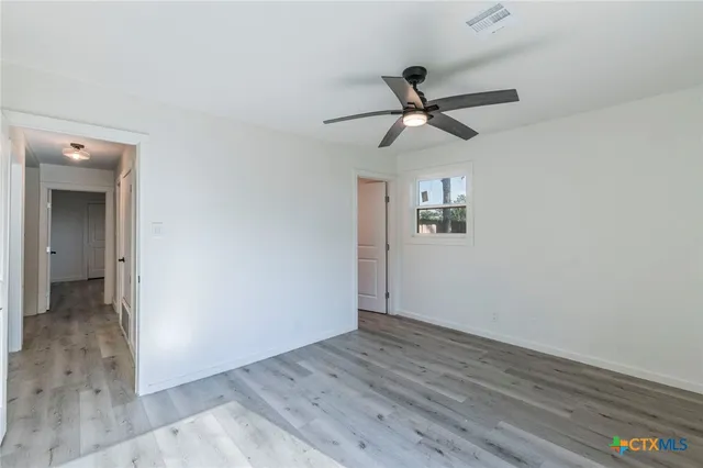 a view of empty room with wooden floor and fan