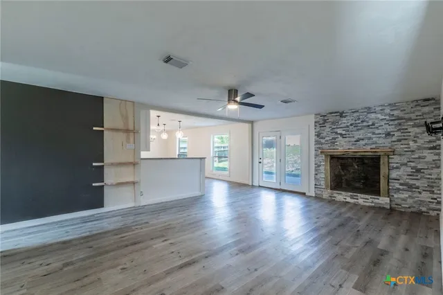 an empty room with wooden floor fireplace and windows