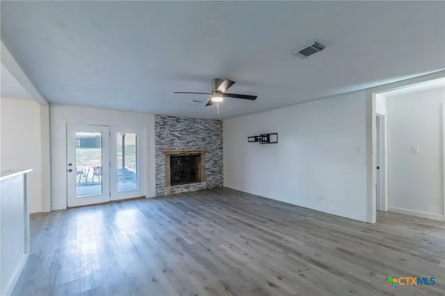 an empty room with wooden floor a fireplace and windows