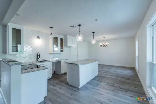 a kitchen with stainless steel appliances granite countertop a sink a stove and a wooden floors