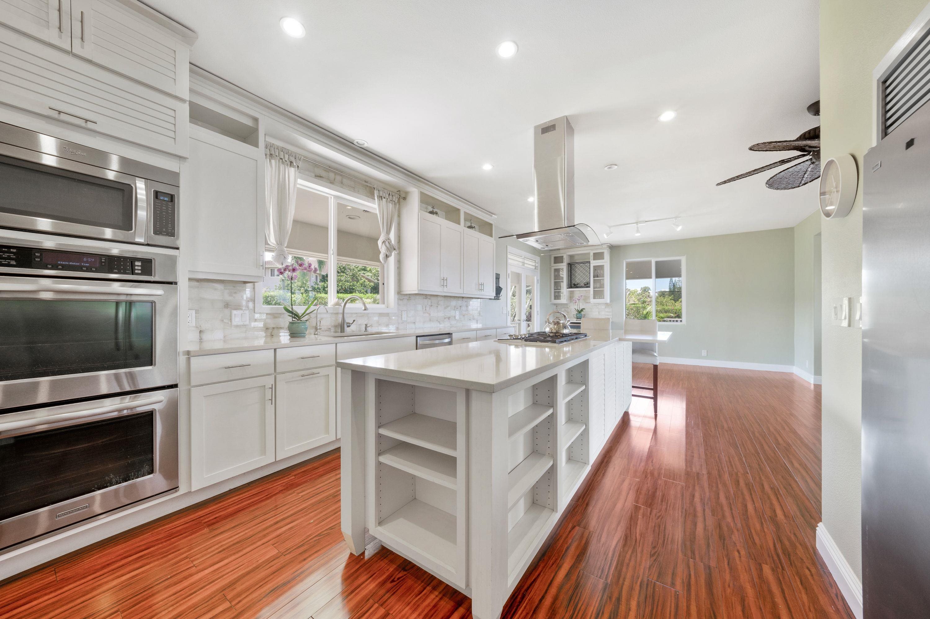 500 North Holokai Place Haiku, HI 96708 - Photo 11 of 30 a white kitchen with wooden floor and stainless steel appliances