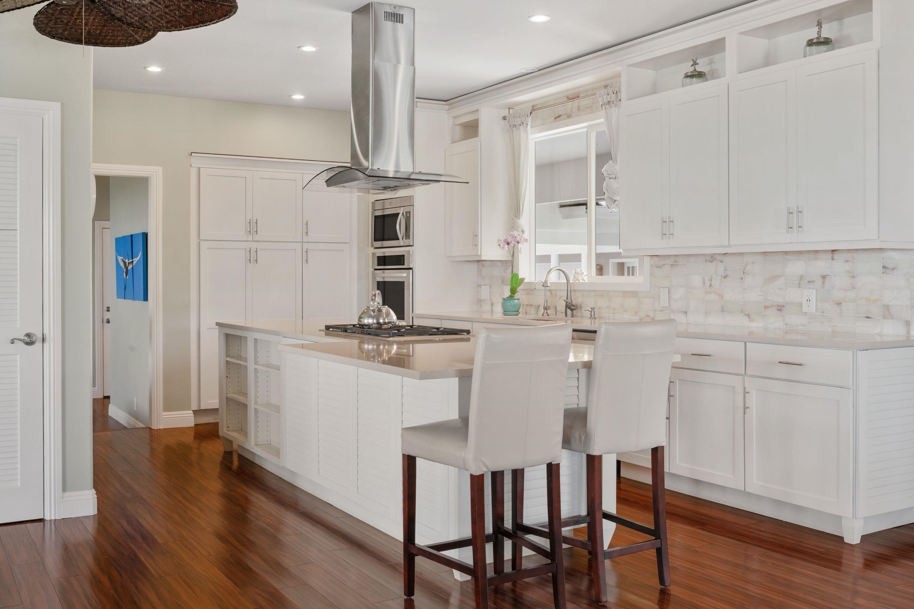 500 North Holokai Place Haiku, HI 96708 - Photo 9 of 30 a kitchen with stainless steel appliances kitchen island granite countertop a table chairs in it and white cabinets