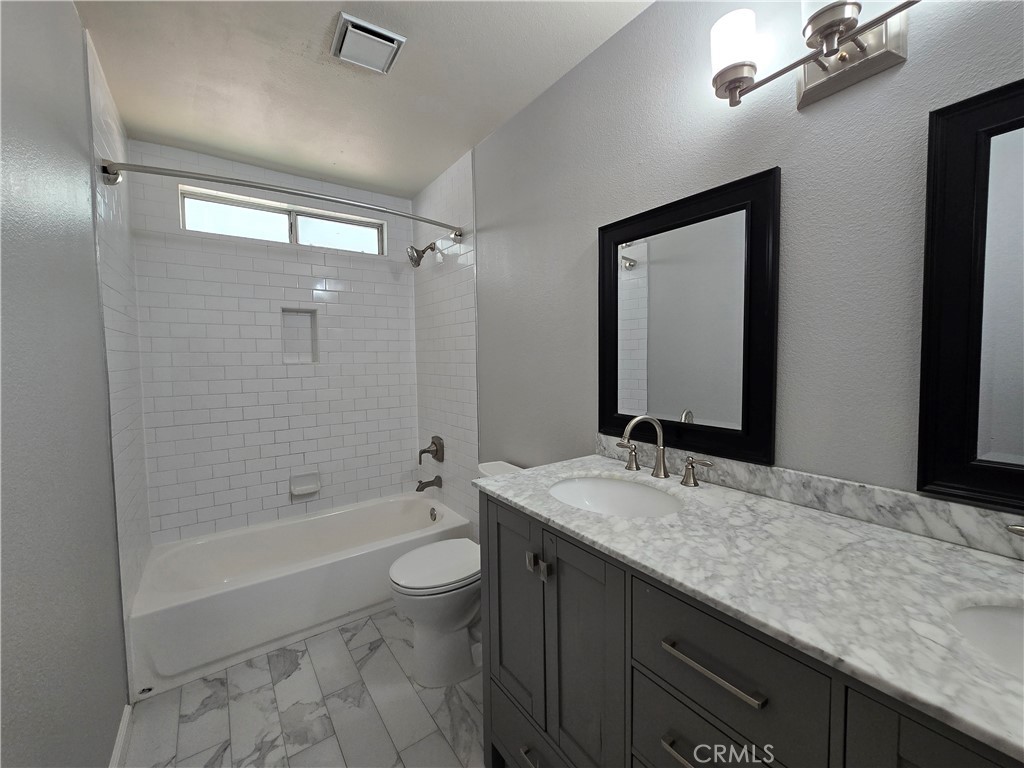 6731 Dove Lane Riverside, CA 92506 - Photo 24 of 28 a bathroom with a granite countertop sink a toilet a mirror and shower