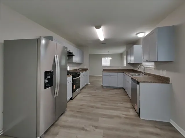 a large kitchen with stainless steel appliances granite countertop a refrigerator and a stove top oven