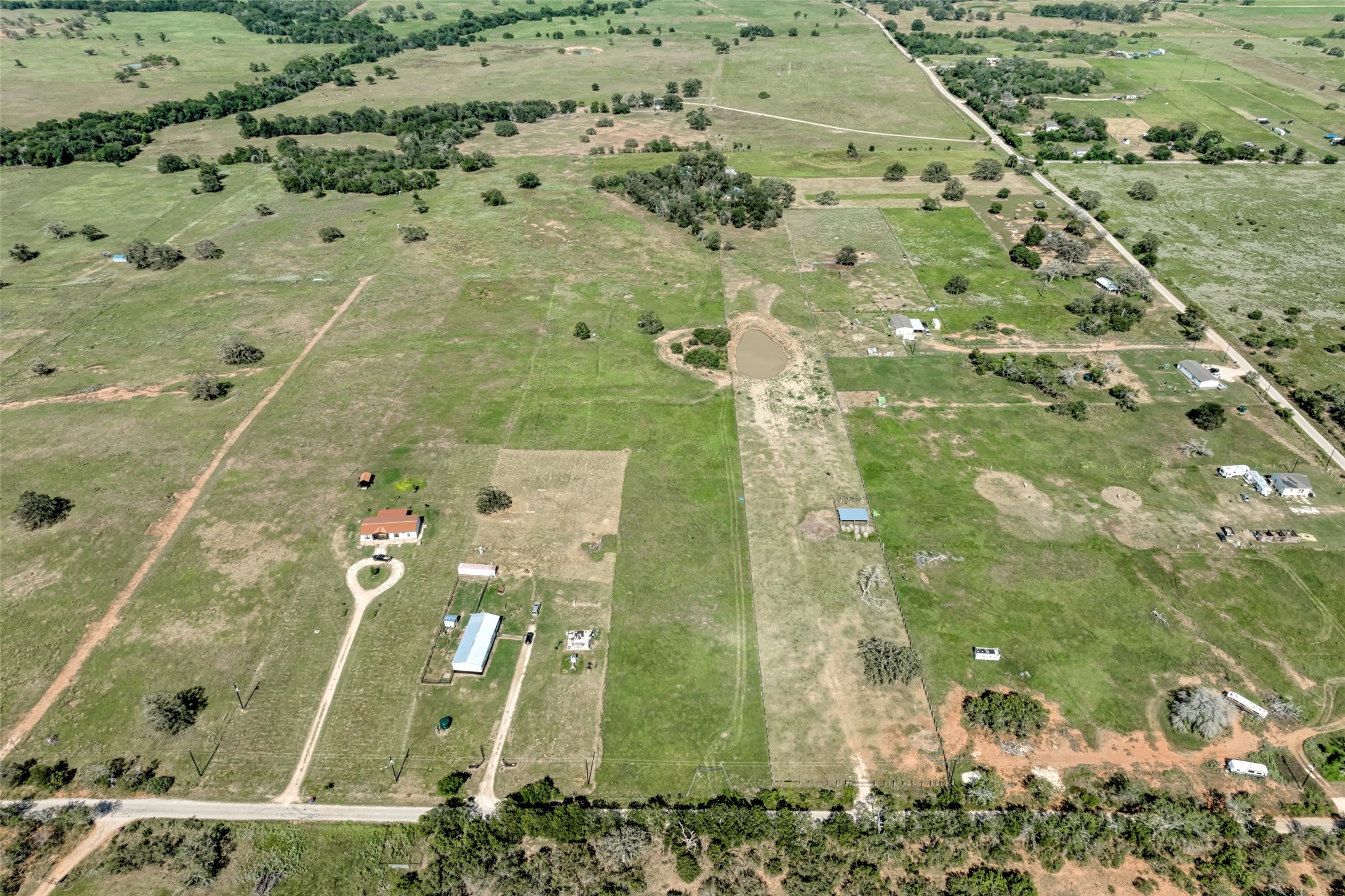 5309 Tenney Creek Road Luling, TX 78648 - Photo 12 of 23 An aerial perspective showcases vast, verdant acreage with a scattered residential footprint and a tranquil pond.