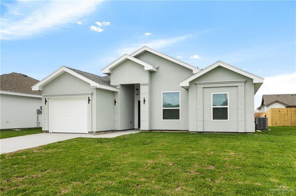 18054 Spruce Street Combes, TX 78552 - Photo 2 of 25 Contemporary stucco exterior featuring a two-car garage, concrete driveway, and established front lawn