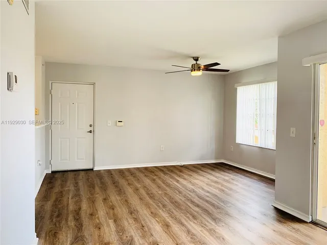 an empty room with a window and a ceiling fan