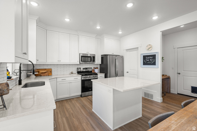 2706 West Maple Street, Unit 285 Mapleton, UT 84664 - Photo 12 of 36 Kitchen featuring white cabinetry, stainless steel appliances, a white subway tile backsplash, light-toned countertops, and wood-finish flooring