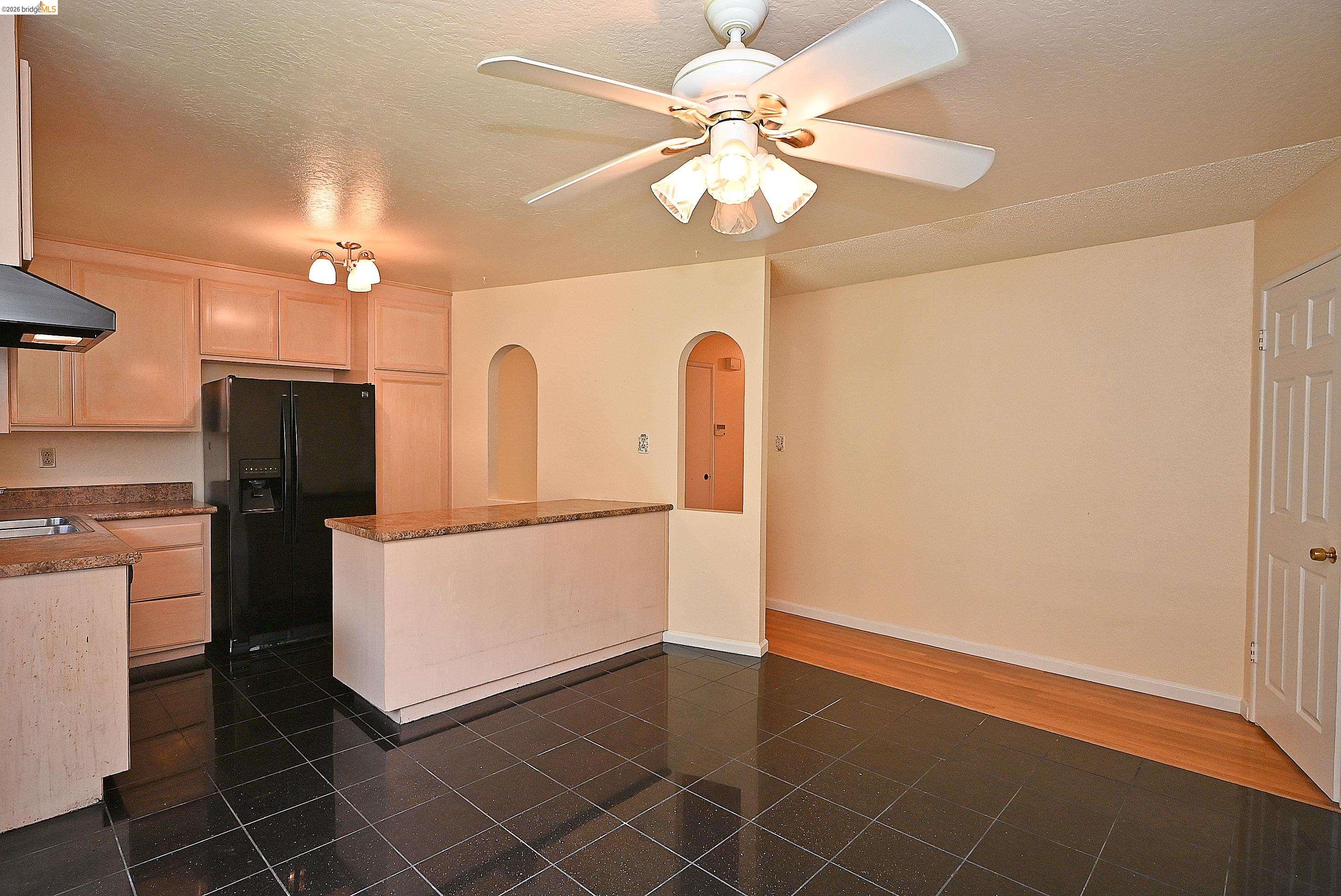 159 Coleridge Drive Vallejo, CA 94591 - Photo 17 of 33 Kitchen with arched walkways, black fridge, light wood finish cabinetry, ceiling fan, and a textured ceiling