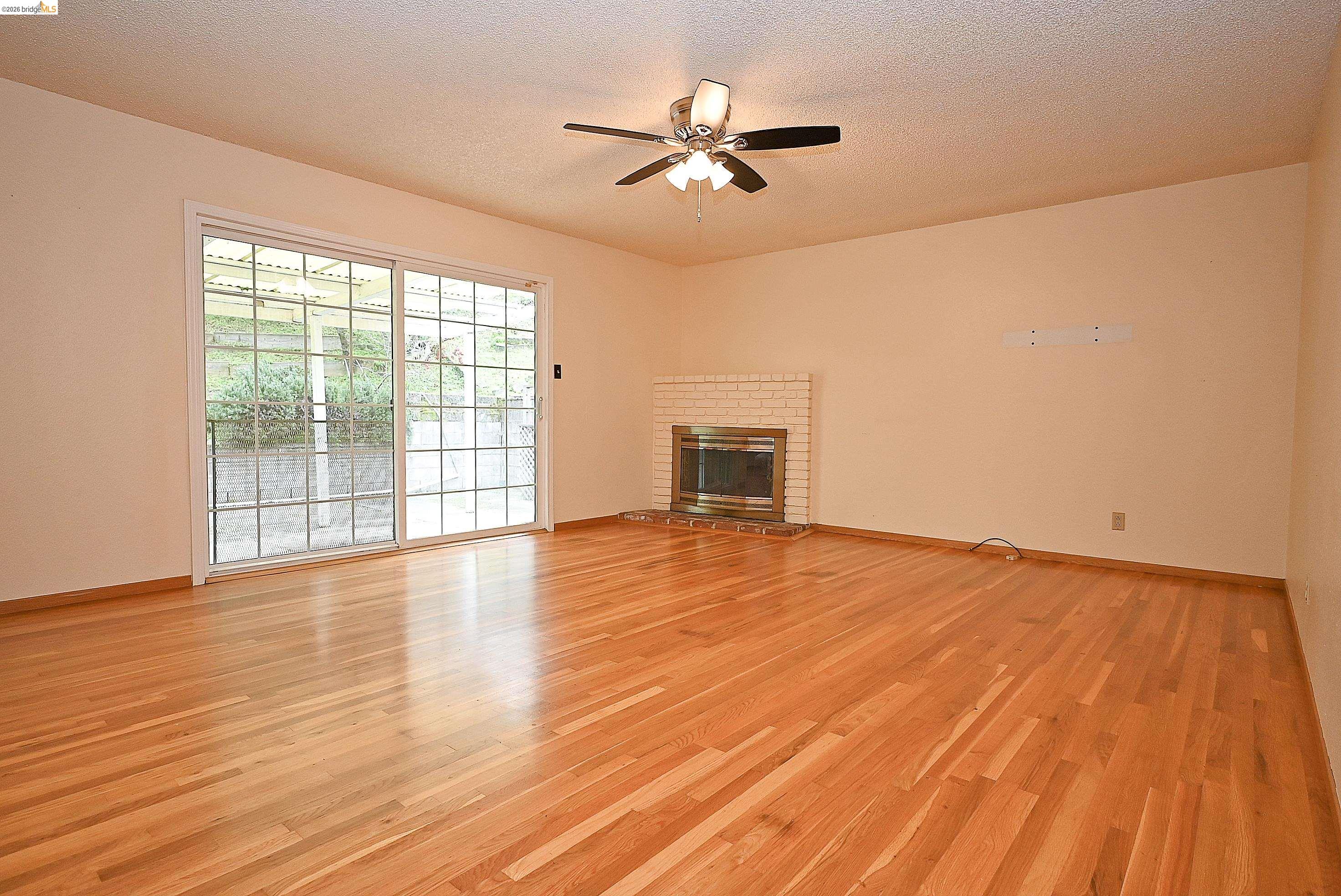 159 Coleridge Drive Vallejo, CA 94591 - Photo 20 of 33 Unfurnished living room with light wood-style flooring, a textured ceiling, a ceiling fan, and a fireplace