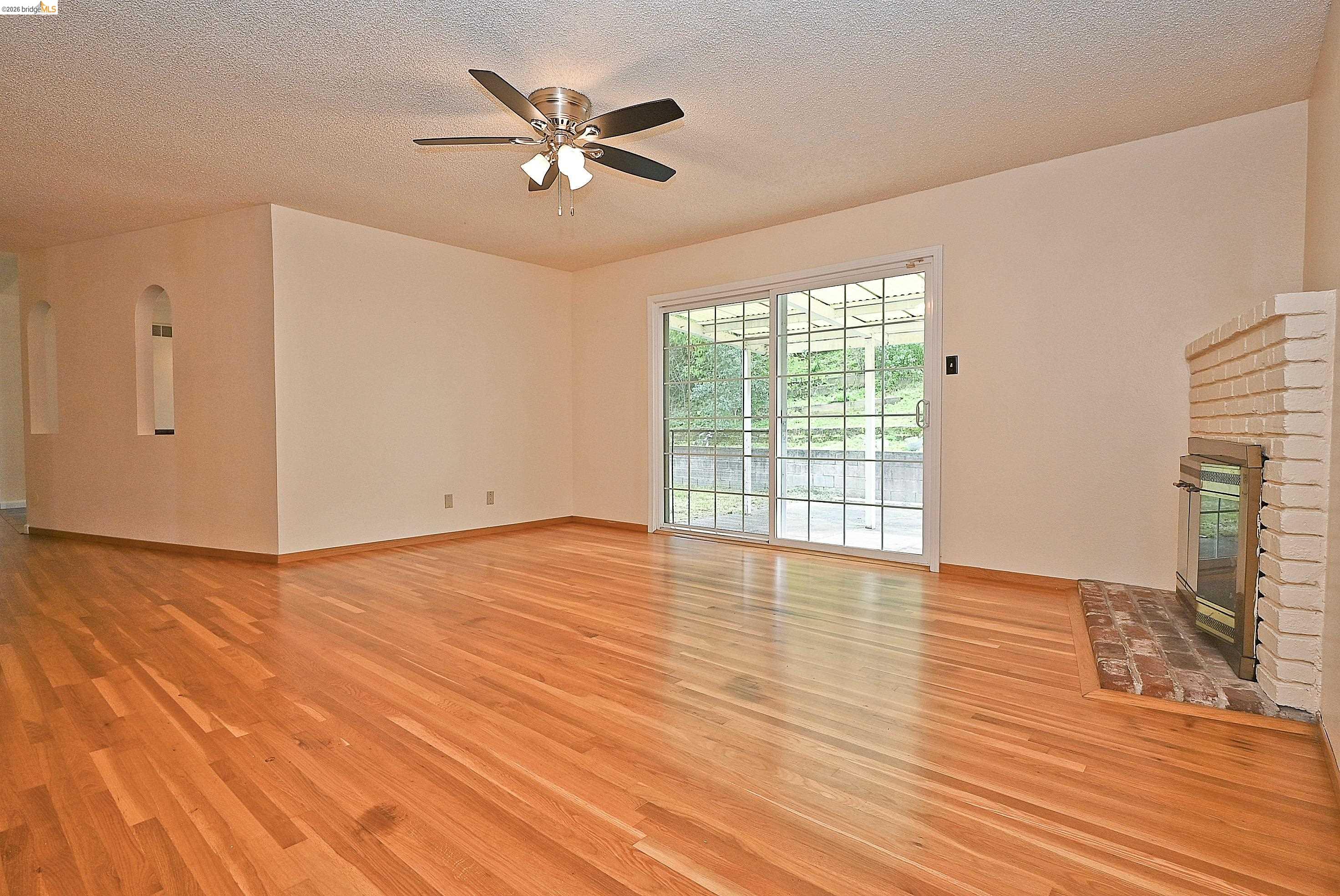 159 Coleridge Drive Vallejo, CA 94591 - Photo 21 of 33 Unfurnished living room featuring a brick fireplace, light wood finished floors, a textured ceiling, and a ceiling fan